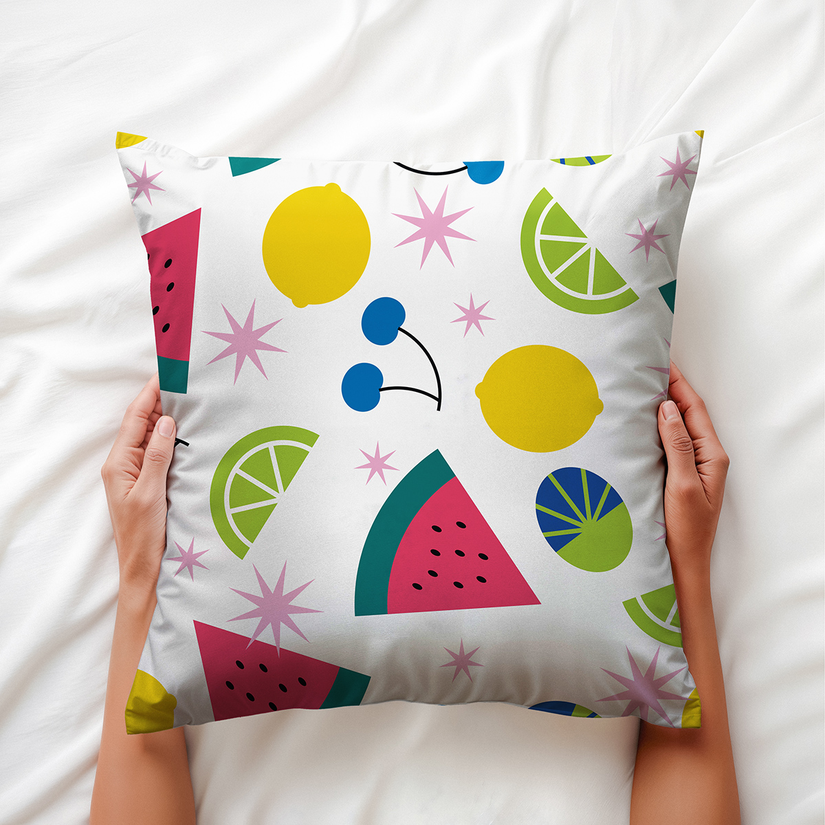 Detal: poduszka ozdobna trzymana w dłoniach, widoczne plasterki arbuza i limonki