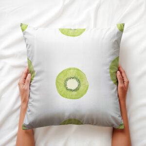 Zbliżenie: dłoń trzymająca poduszkę z motywem kiwi, pokazujące fakturę tkaniny i nadruku