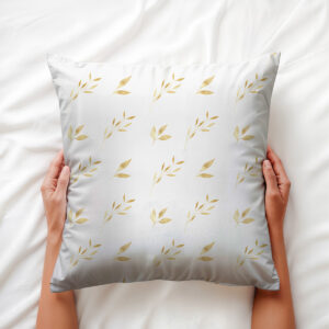widok z góry: dłonie trzymają poduszkę z subtelnym motywem złotych liści