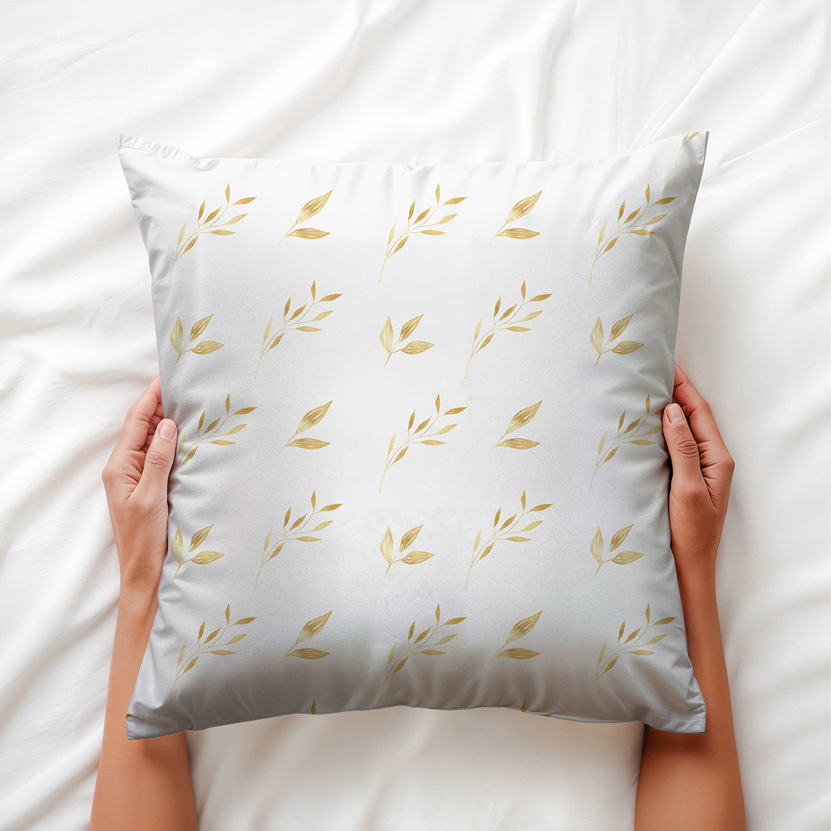 widok z góry: dłonie trzymają poduszkę z subtelnym motywem złotych liści