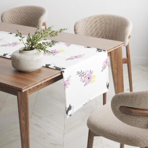 Bieżnik opadający na krawędź stołu z dekoracyjną rośliną w donicy