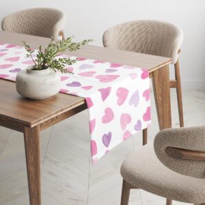 Bieżnik ułożony wzdłuż drewnianego stołu, widoczne rozproszone serca na białym tle