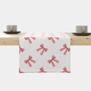 Bieżnik na stole z powtarzającym się wzorem różowych kokardek na jasnym tle