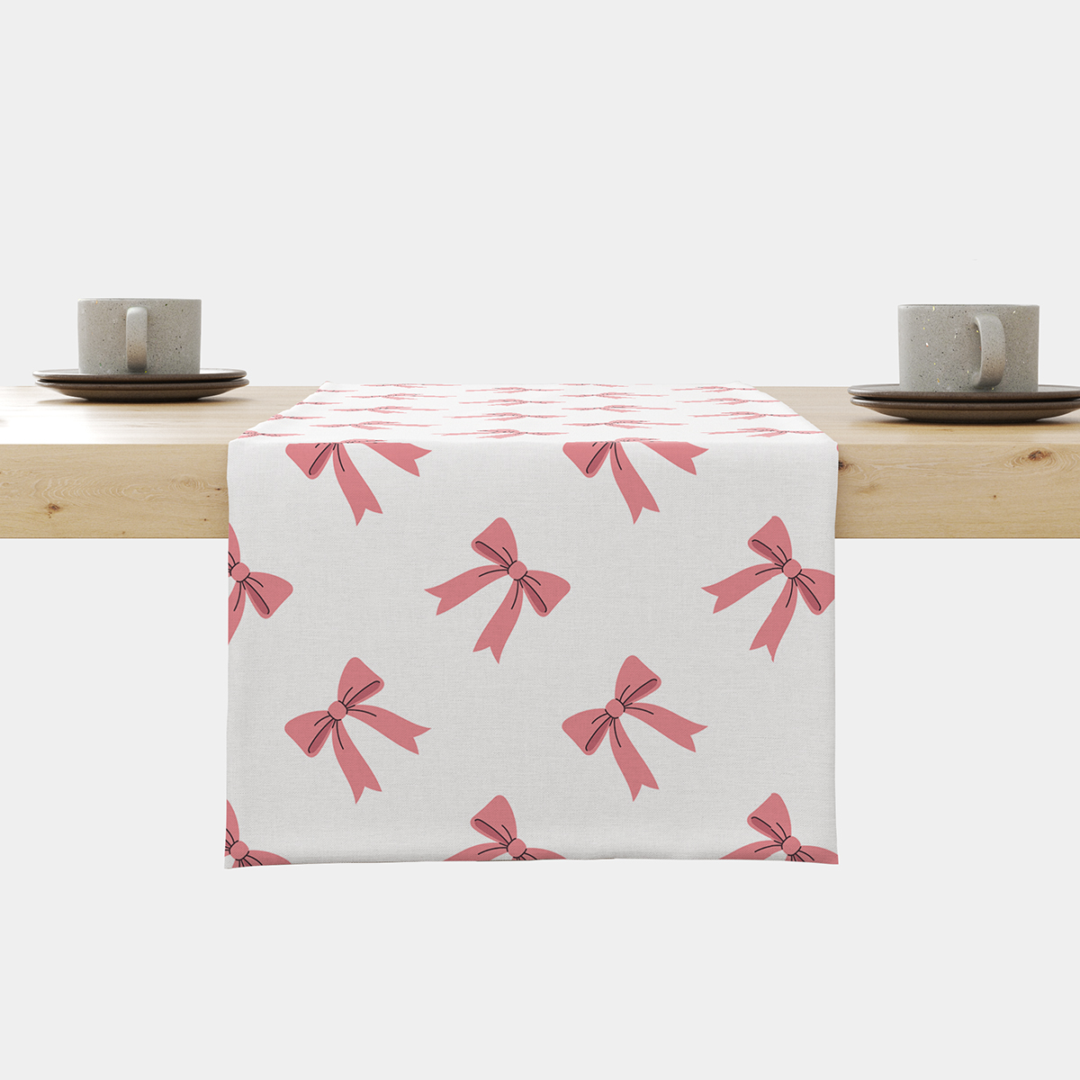 Bieżnik na stole z powtarzającym się wzorem różowych kokardek na jasnym tle