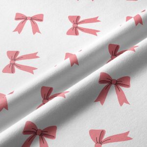 Zbliżenie na materiał pokazujące nadruk różowych kokardek i fakturę tkaniny