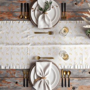Stół nakryty z bieżnikiem, talerze i złote sztućce w aranżacji