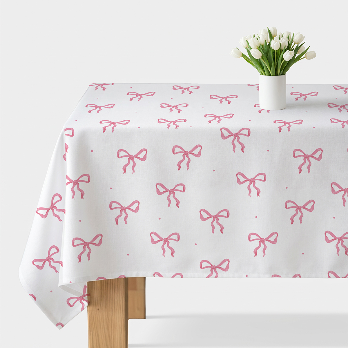 Obrus rozłożony na stole z powtarzalnym wzorem różowych kokard, ujęcie z góry