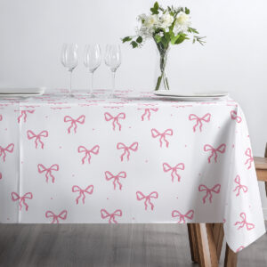 Widok z boku na stół udekorowany kieliszkami i bukietem na obrusie z motywem kokard