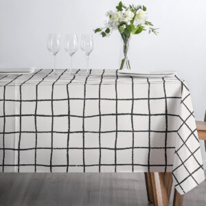 zbliżenie narożnika stołu pokazujące krawędź obrusa i wzór kraty