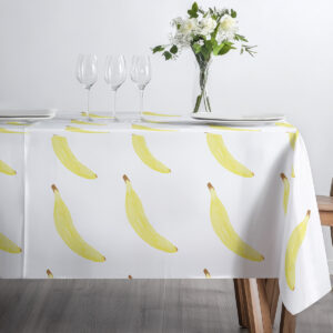 Stół nakryty obrusem z bananami przygotowany ze szkłem i talerzami