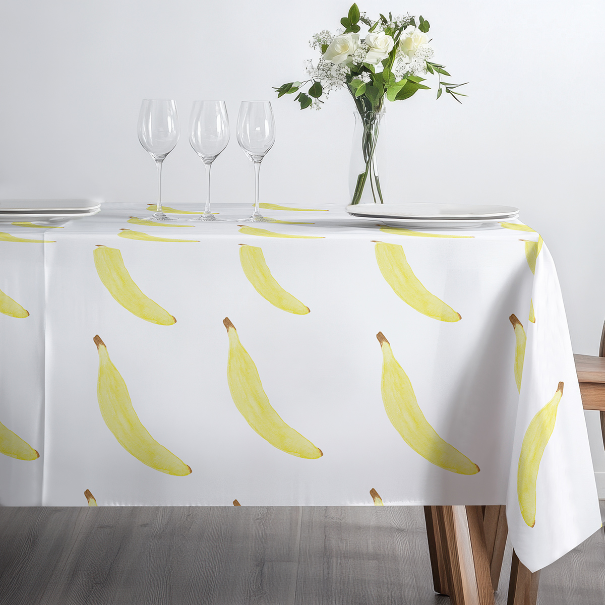 Stół nakryty obrusem z bananami przygotowany ze szkłem i talerzami