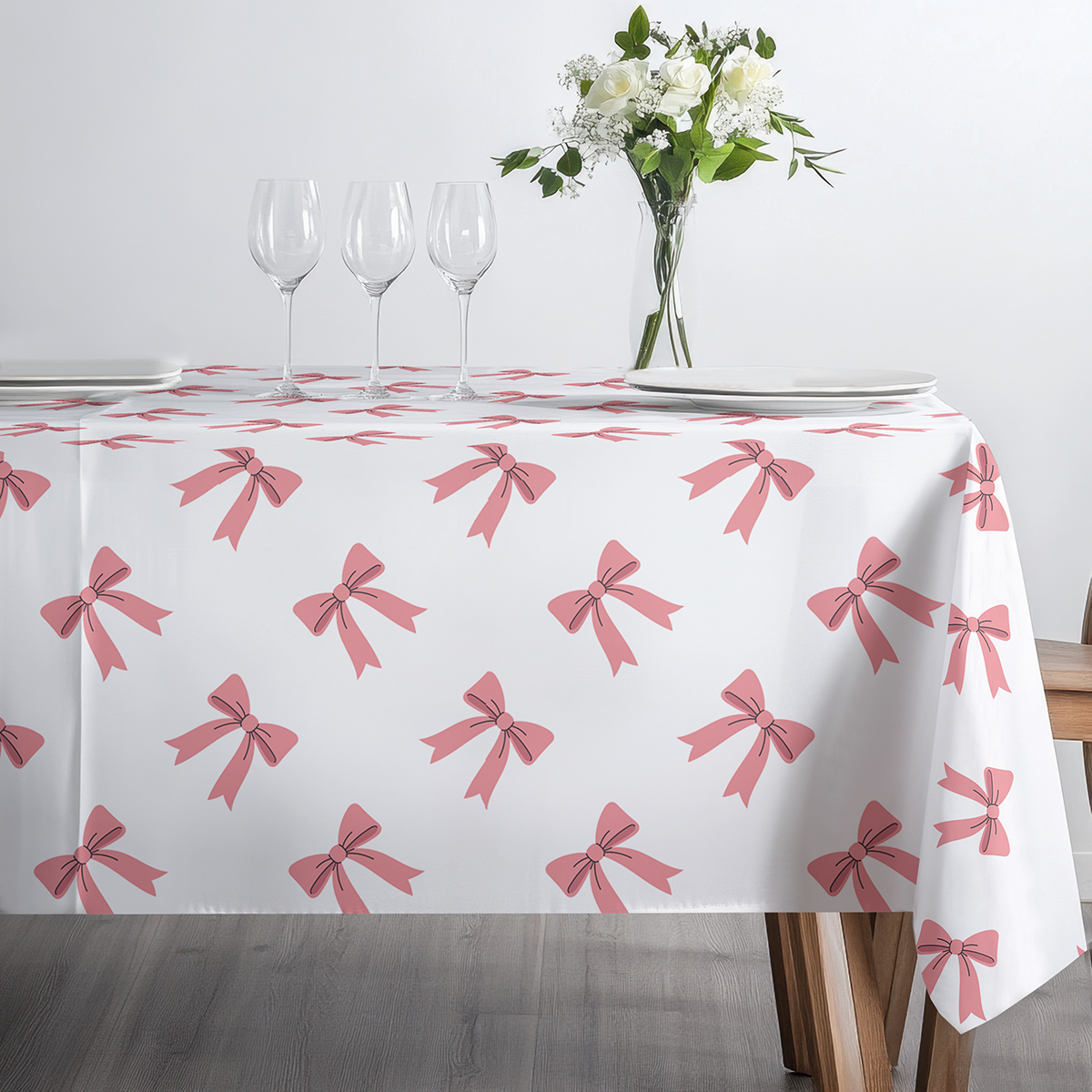 jasne wnętrze z filiżanką i kieliszkami na obrusie ozdobionym różowymi kokardkami