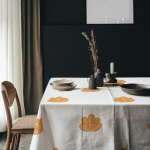 aranżacja stołu z obrusem, ceramicznymi naczyniami i dekoracjami w minimalistycznym wnętrzu