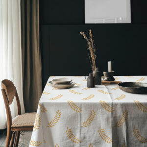 aranżacja stołu z obrus z motywem złotych gałązek na tle ciemnej ściany