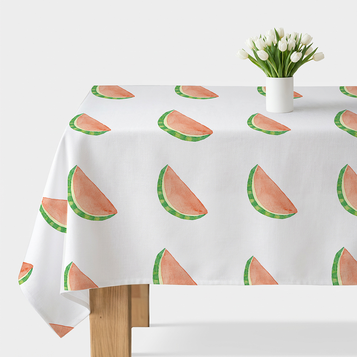 obrus z akwarelowymi plasterkami arbuza na białym stole z wazonem tulipanów