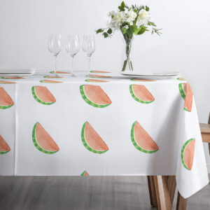 stół nakryty obrusem z arbuzowymi plasterkami z ustawionymi kieliszkami i talerzami