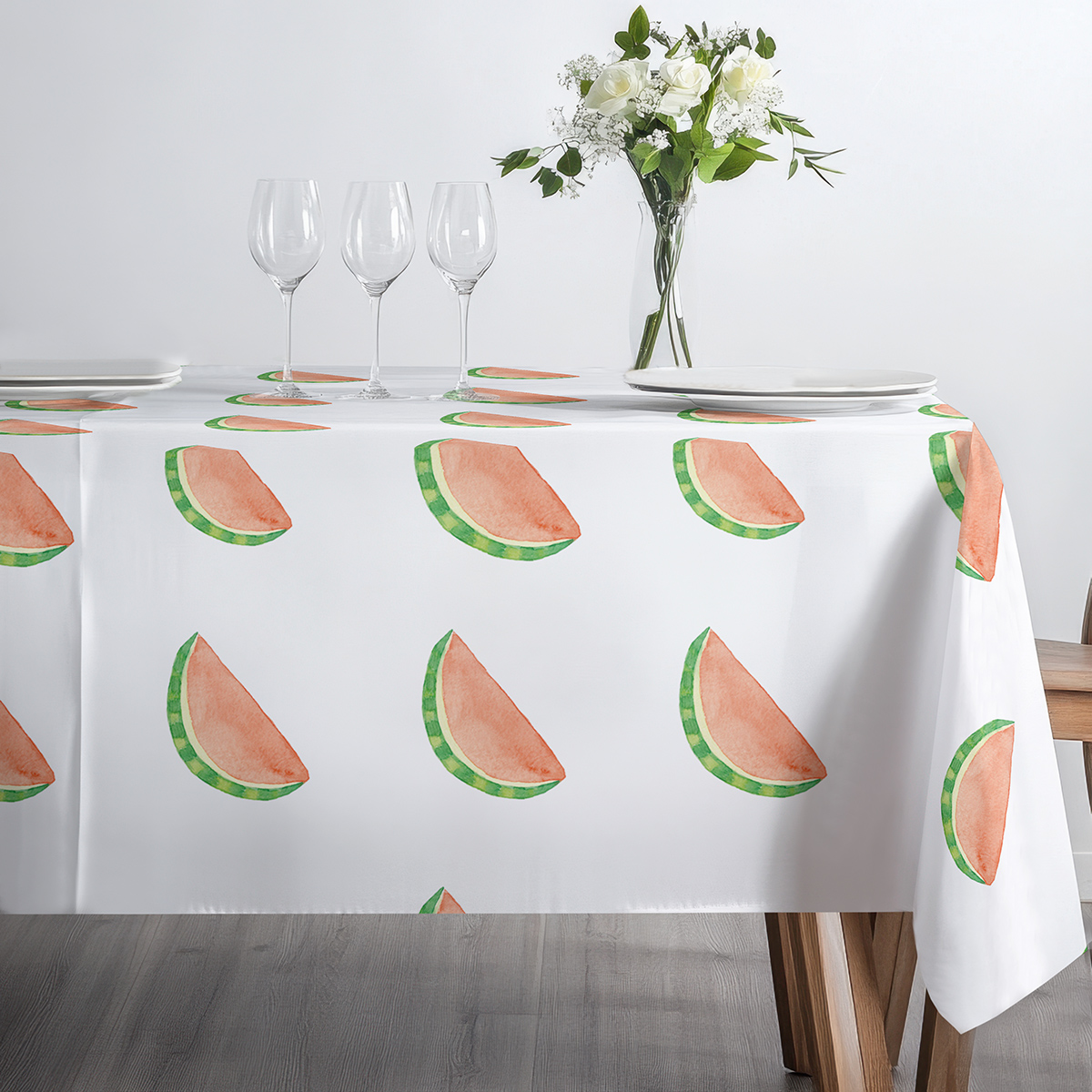 stół nakryty obrusem z arbuzowymi plasterkami z ustawionymi kieliszkami i talerzami