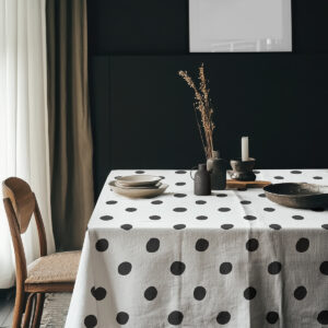 aranżacja stołu z obrusem w kropki, ceramiczne naczynia i dekoracje na tle ciemnej ściany
