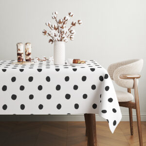 stół z obrusem w czarne kropki udekorowany wazonem z gałązkami bawełny i deserami