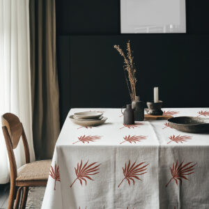 aranżacja stołu z talerzami i dekoracyjnymi naczyniami na obrusie z motywem palmowych liści