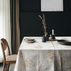 aranżacja stołu z naczyniami i dekoracyjnymi akcentami na obrusie z subtelnym złotym wzorem