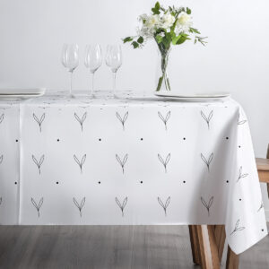 minimalistyczne nakrycie stołu ze szkłem i wazonem kwiatów na jasnym obrusie z listkami