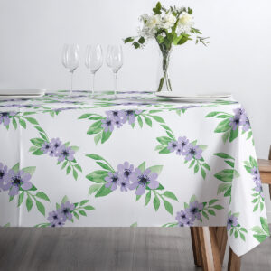 Stołowa aranżacja z kieliszkami i wazonem ustawiona na obrusie z fioletowymi kwiatami