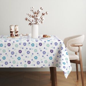 Stół nakryty obrusem z motywem kwiatowym w jasnym wnętrzu z dekoracyjnym wazonem