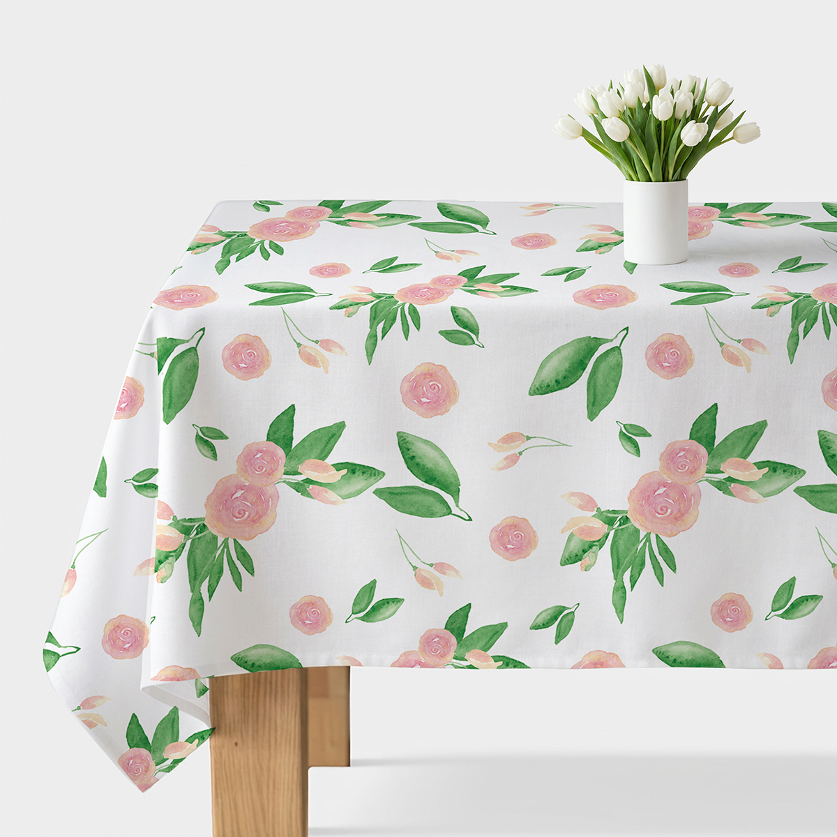 obrus rozłożony na stole z różowymi pąkami i zielonymi liśćmi