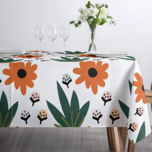 zbliżenie górnej części stołu z zastawą na obrusie, pokazujące pomarańczowe kwiaty i zielone liście