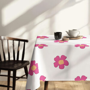 stół nakryty obrusem z widocznymi różowymi motywami kwiatowymi i naczyniami