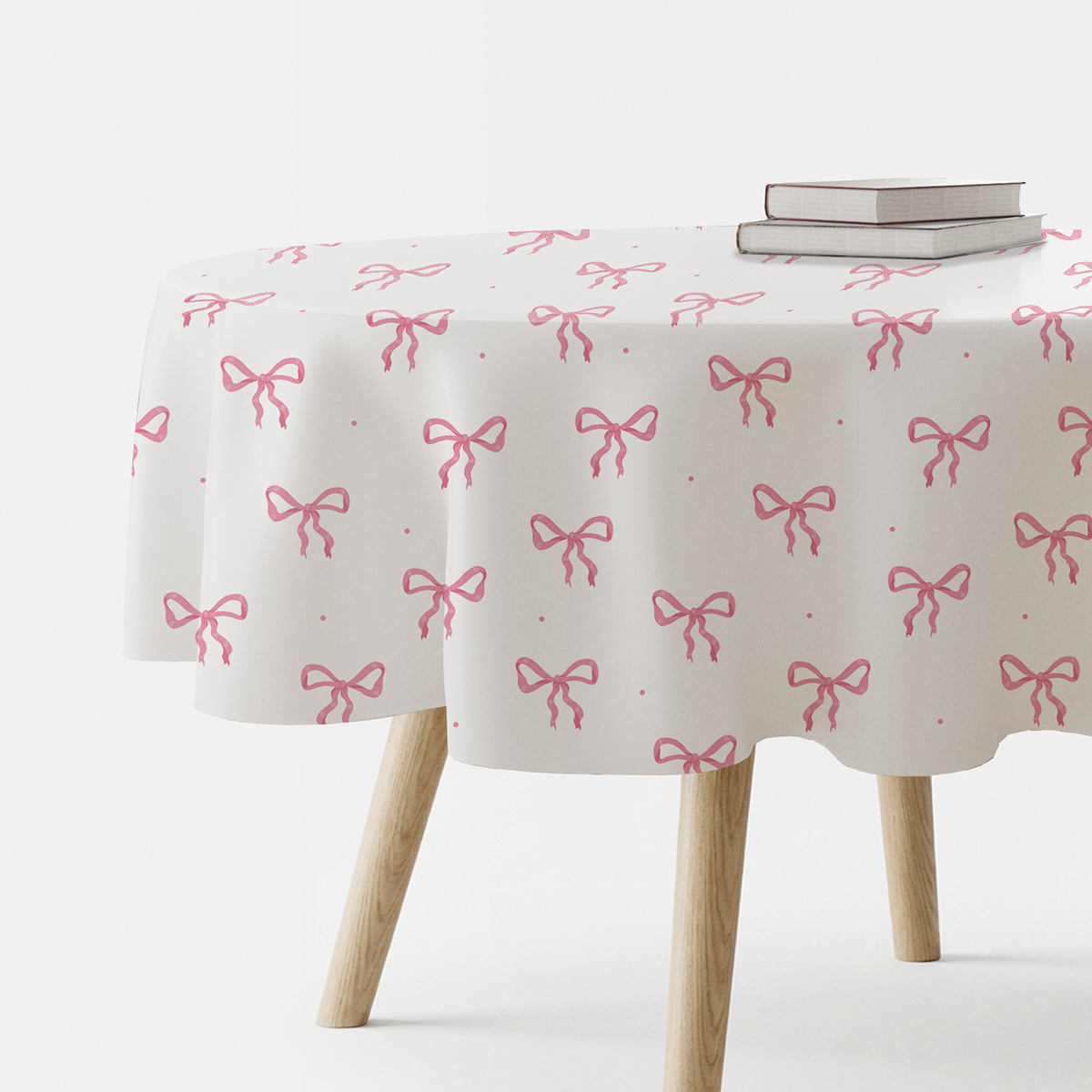 okrągły obrus na stole z drobnymi różowymi kokardkami, aranżacja z książkami