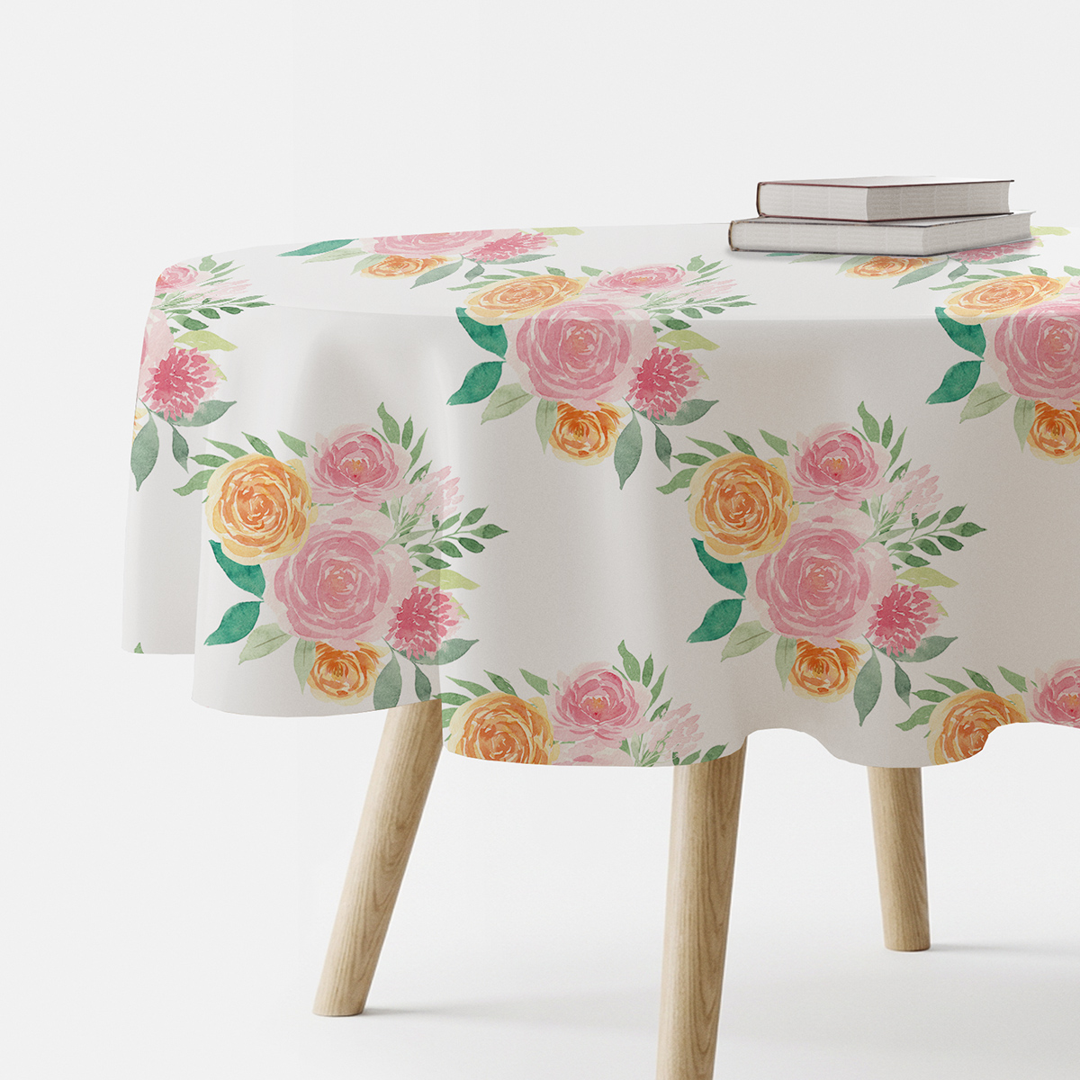 okrągły stół nakryty obrusem z akwarelowymi bukietami, na obrzeżu książki