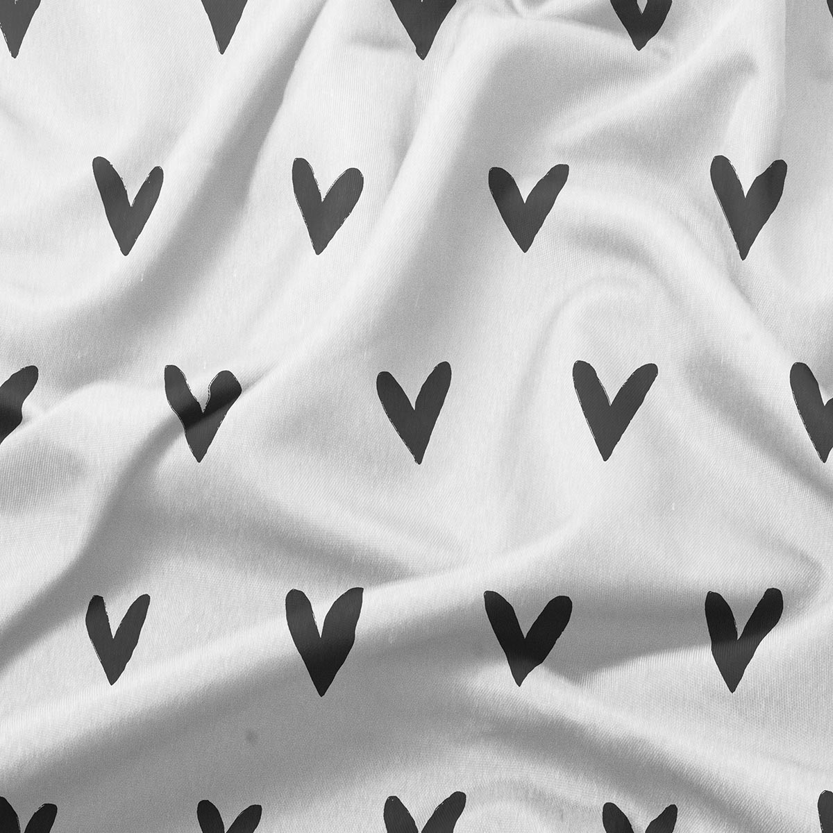 detal tkaniny z czarnymi ręcznie malowanymi serduszkami na białym tle