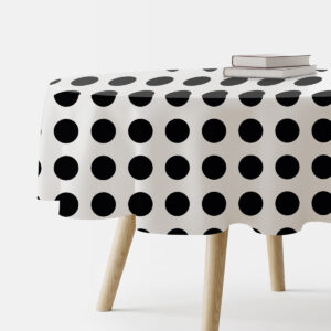 Okrągły obrus w duże czarne groszki na białym tle, ujęcie boczne stołu z książkami