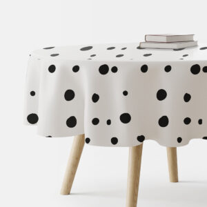 Okrągły obrus z nieregularnymi czarnymi grochami na białym tle, widok z boku stołu