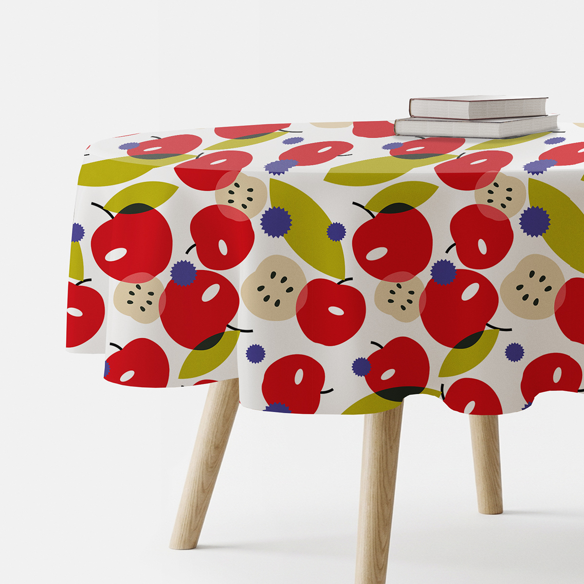 okrągły obrus na stole z widocznym wzorem czerwonych jabłek i oliwkowych liści