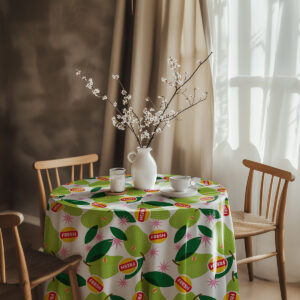 aranżacja stołu z obrusem w zielone gruszki, wazonem i porcelaną w przytulnym wnętrzu