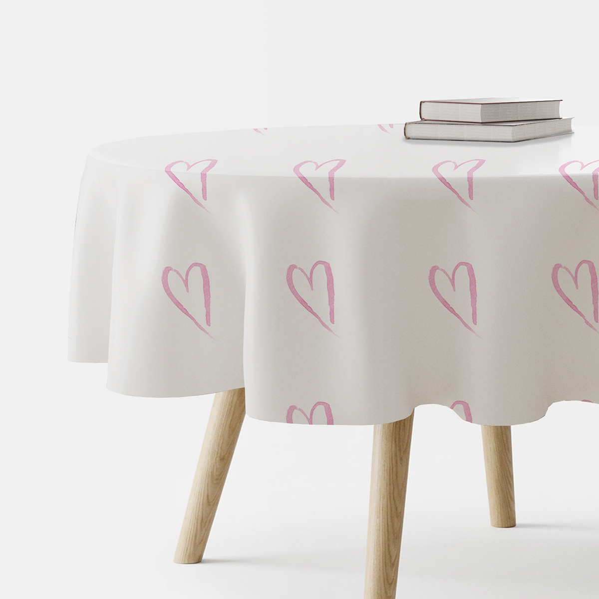 okrągły stół nakryty białym obrusem z różowymi akwarelowymi sercami, widok na brzeg stołu