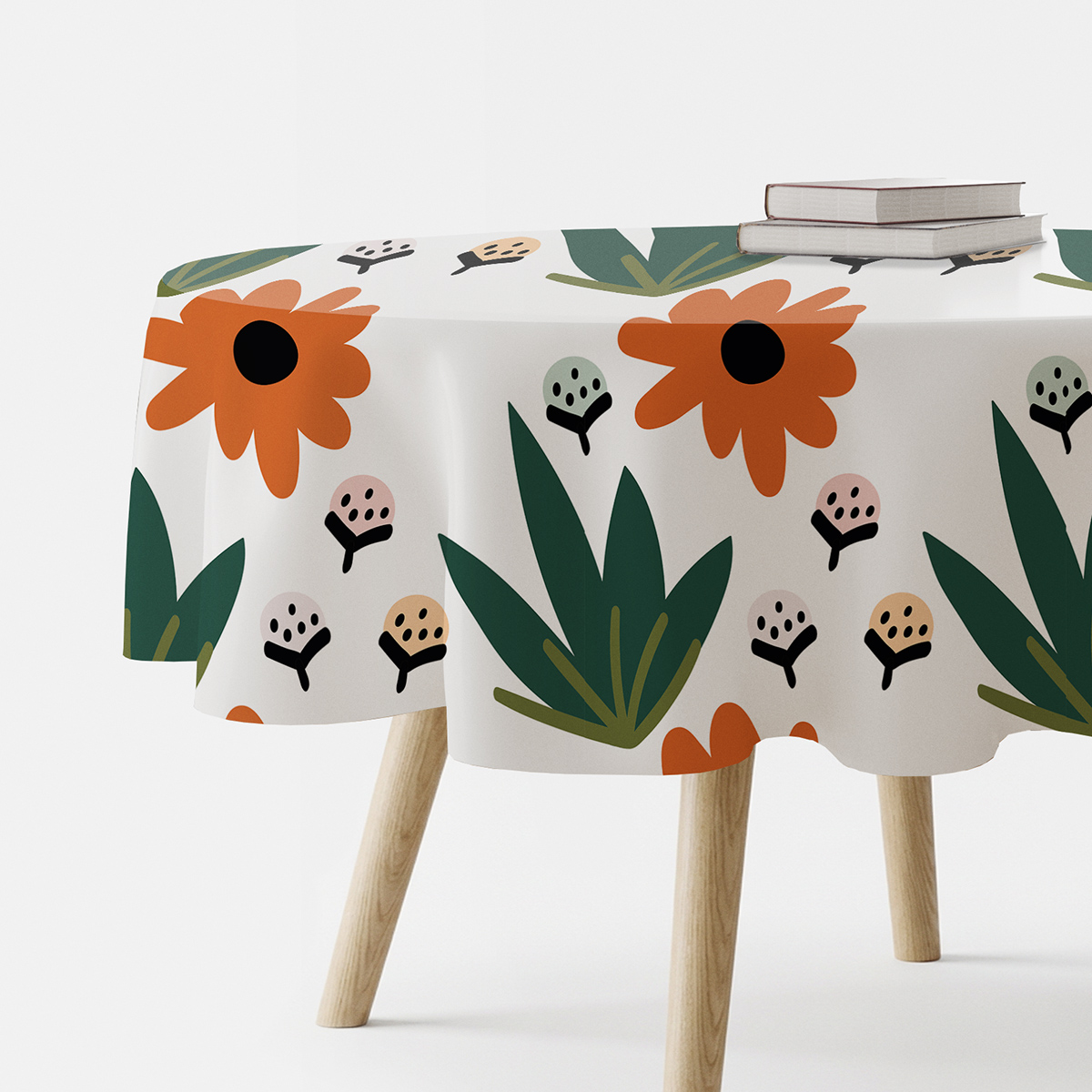 okrągły obrus na stole z dużymi pomarańczowymi kwiatami i zielonymi liśćmi