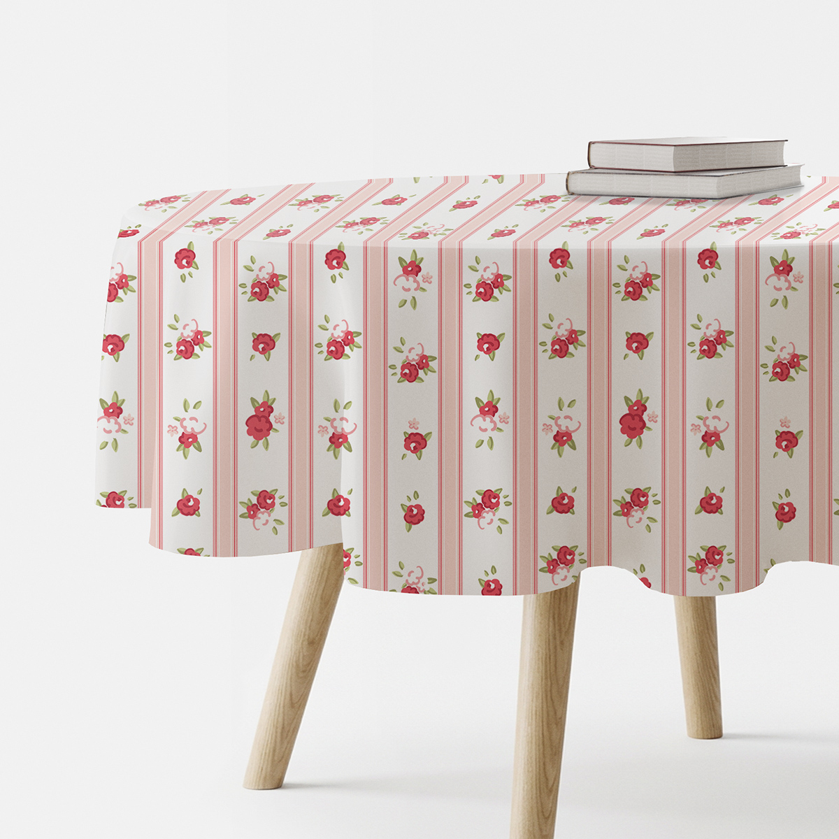 Okrągły obrus z wzorem małych czerwonych różyczek i pionowych różowych pasów, ujęcie z boku