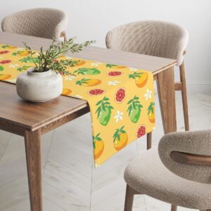 Widok końca stołu z bieżnikiem w owocowy wzór i naturalną dekoracją wazonu