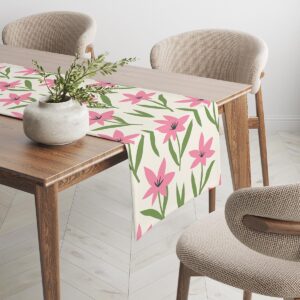 Bieżnik rozłożony na drewnianym stole z dekoracyjną donicą i krzesłami w tle