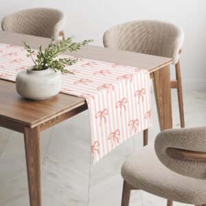 Bieżnik rozłożony na drewnianym stole, widoczny brzeg i delikatny motyw kokardek