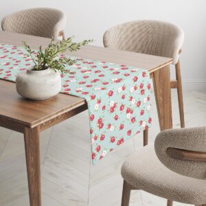 bieżnik rozłożony na długim stole z wazonem, ukazujący powtarzalny motyw różyczek