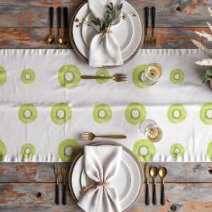 aranżacja stołu z bieżnikiem w plastry kiwi, talerze, złote sztućce i kieliszki
