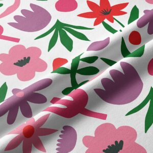 Zbliżenie tkaniny z wyraźnym nadrukiem różowych i czerwonych kwiatów oraz zielonych liści