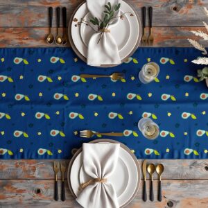 Aranżacja stołu z bieżnikiem, zastawą i sztućcami, widoczny motyw awokado i kwiatków