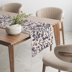 Fragment bieżnika zwisający z nowoczesnego stołu obok wazonu i neutralnych krzeseł