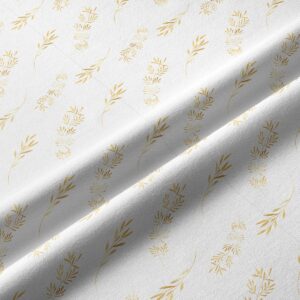 Zbliżenie tkaniny pokazujące złoty nadruk gałązek i fakturę materiału